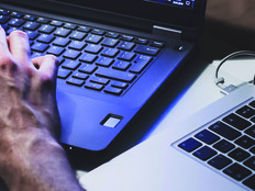 Hands working on two laptops