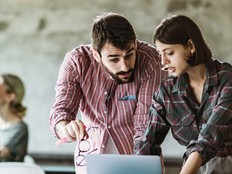 An instructor works with a student at a computer.