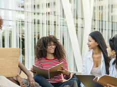 A group of students chat outside on a college campus