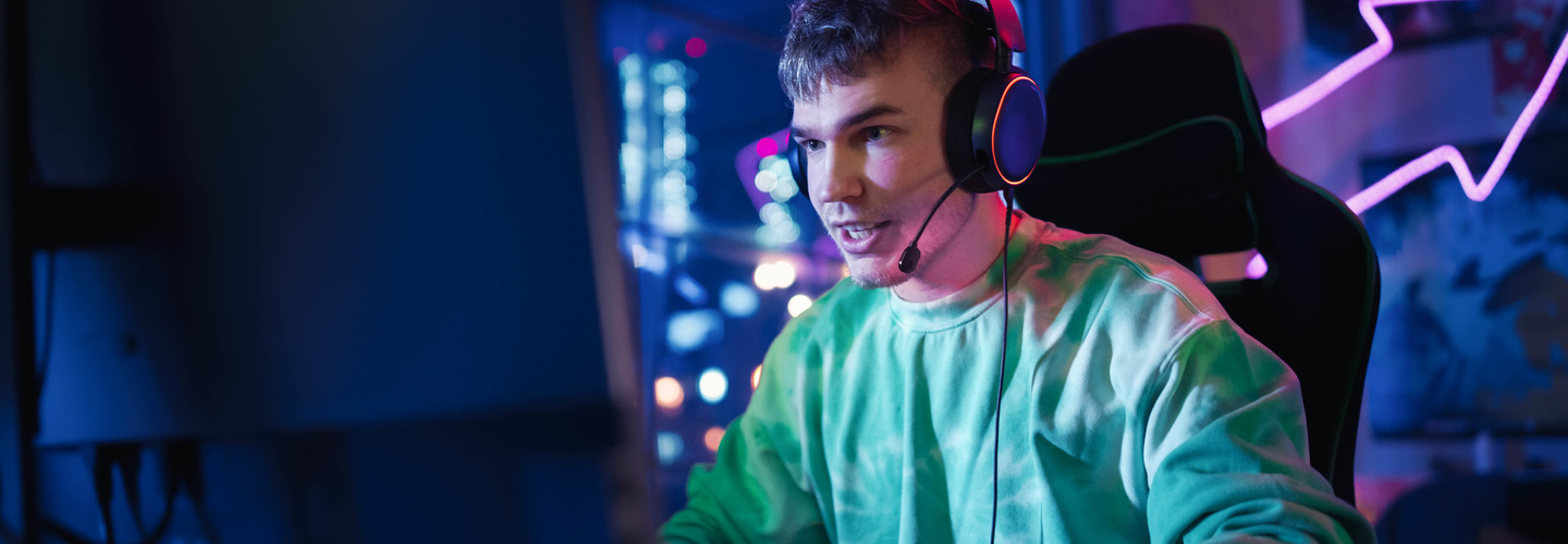 Gamer Wearing Headphones and Playing Online Game on Personal Computer.