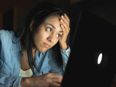 student sitting in the dark looking upset at computer screen